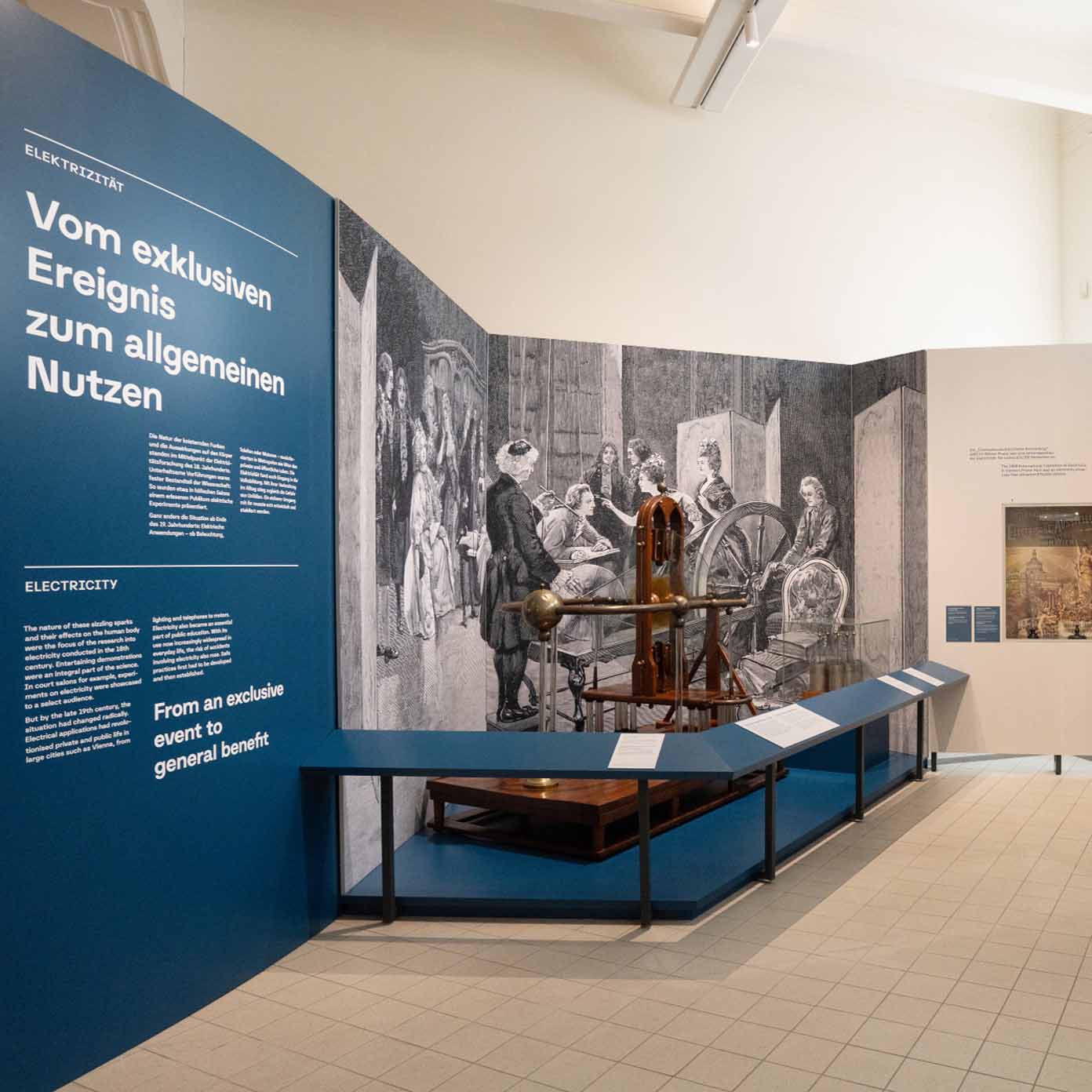 Gesamtansicht der Ausstellungsgrafik „Wirtschaft im Wandel" im Technischen Museum Wien – Blauer Themenbereich Elektrizität mit bedruckten Stoffbespannungen in Alu-Frames, Folienplots und Beschriftungen, umgesetzt durch print-art 2026